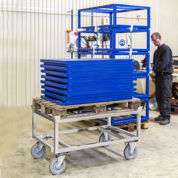 Stapel blaue Metallplatten auf einem Palettenwagen in einer Werkstatt