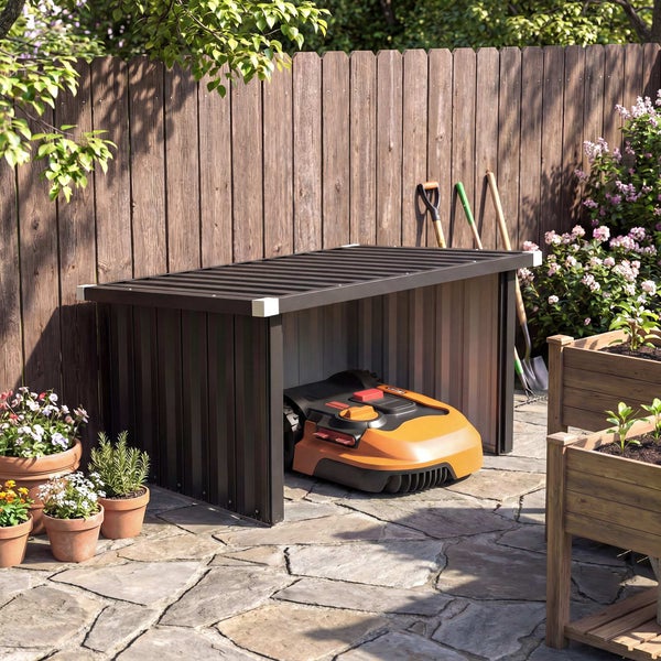 Graues Gerätehaus aus Kunststoff mit weißem Rahmen und geöffneter Tür, das Regalsysteme im Inneren zeigt, auf einer Holzterrasse im Garten.