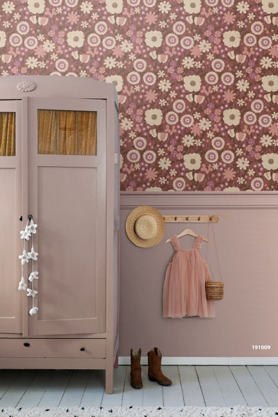 Vintage-Kinderzimmer gestaltet mit floraler Tapete, einem antiken Holzschrank und einer Wandgarderobe mit Kinderkleidung.