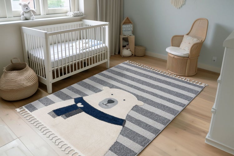 Kinderzimmer mit einem Teppich mit Eisbär Motiv und Streifenmuster sowie einem Gitterbett und einem Rattansessel auf einem hellen Holzboden.