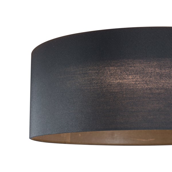 Detailansicht eines runden Lampenschirms aus schwarzem Textilgewebe mit goldfarbener Innenseite.