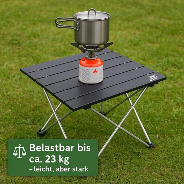 Schwarzer Campingtisch mit Topf und Gaskocher im Freien auf Rasen