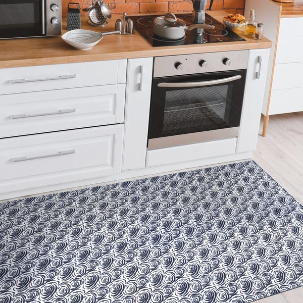 Küchenszene mit Küchenteppich mit Rosenmuster vor weißen Küchenschränken.