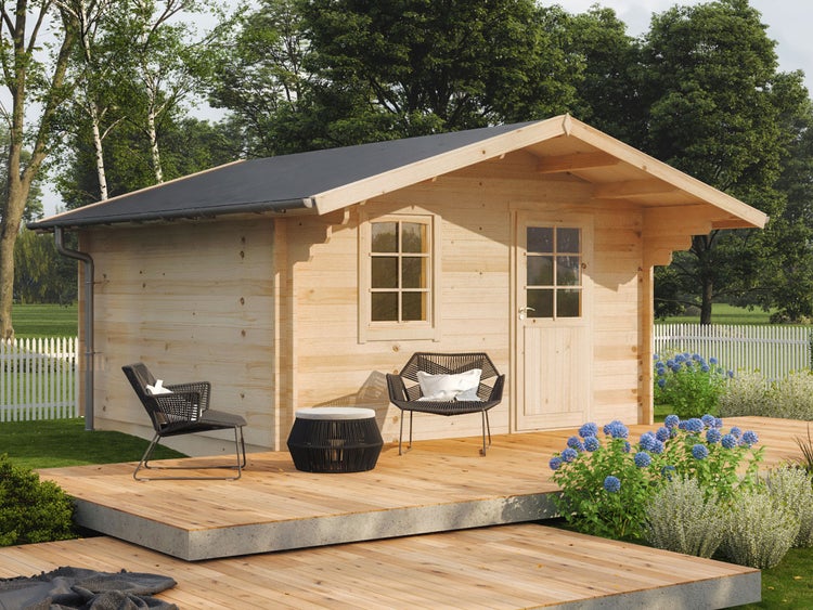 Ein Gartenhaus aus Holz mit Satteldach auf einer Holzterrasse mit zwei Loungesesseln und einem Beistelltisch in einem grünen Garten.