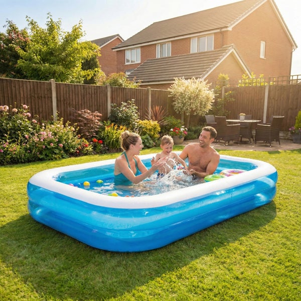 Familie spielt in einem rechteckigen aufblasbaren Planschbecken im Garten vor einem Wohnhaus.