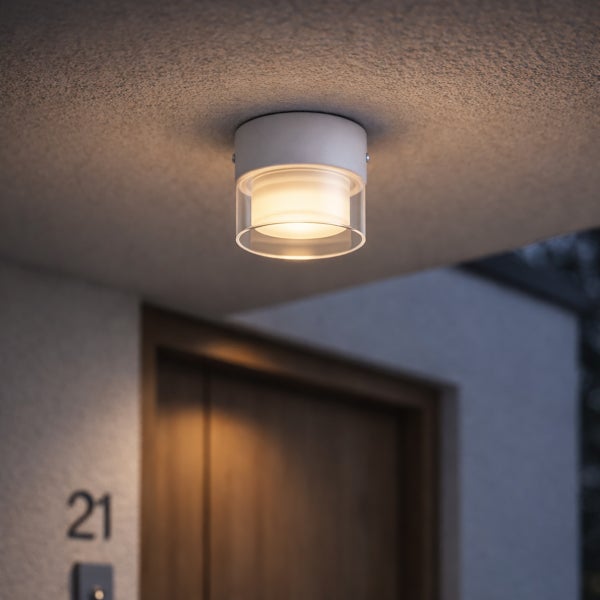 Moderne Außen-Deckenleuchte, zylindrisch, Metall mit doppeltem Glas, leuchtend montiert unter einem Vordach am Hauseingang.