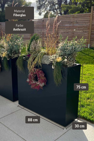 Anthrazitfarbener Pflanzkübel aus Fiberglas, Maße 88 mal 30 mal 75 Zentimeter, bepflanzt in einem Garten vor einem Holzzaun.