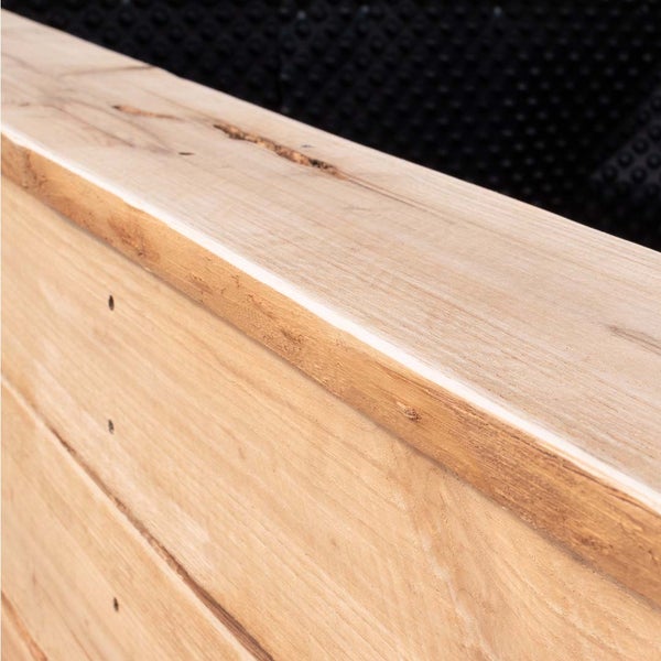 Detailansicht eines Hochbeets aus unbehandeltem Holz mit rustikaler Maserung und integrierter Noppenbahn für den Garten.