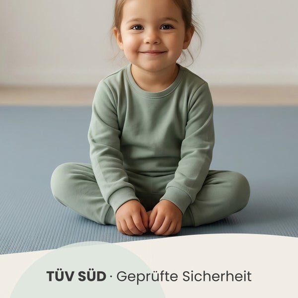 Kind sitzt auf einer strukturierten Matte, TÜV SÜD geprüfte Sicherheit.