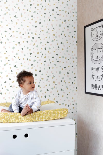 Kinderzimmer mit Wickelkommode, dekorativer Tapete und einem Baby