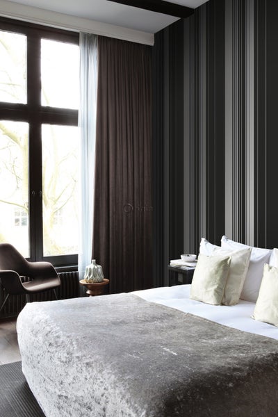 Schlafzimmer mit Bett, Vorhängen und gestreifter Tapete