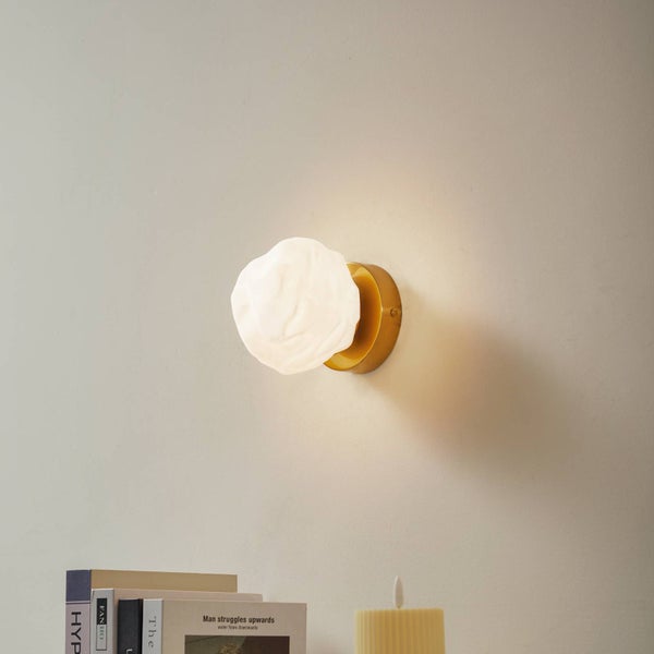 Moderne Wandleuchte mit strukturiertem Glas-Schirm in Steinoptik und runder Messing-Halterung.