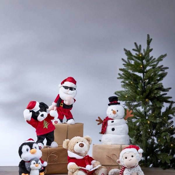 Dekorative Szene mit Weihnachtsfiguren aus Plüsch, darunter ein Weihnachtsmann, ein Schneemann, ein Bär, ein Affe, ein Pinguin, ein Hund und ein Weihnachtsbaum.