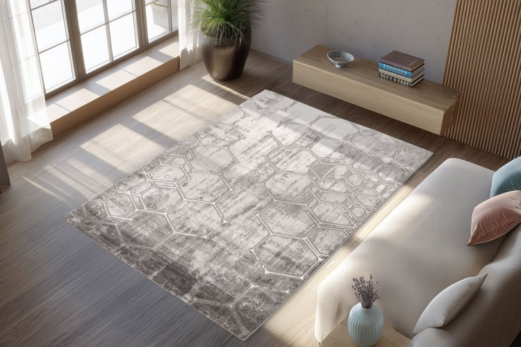 Moderner Wohnzimmerteppich mit geometrischem Sechseckmuster in einem lichtdurchfluteten Raum mit Holzmöbeln und weichem Sofa.