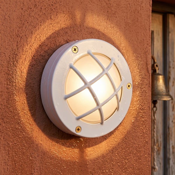 Runde LED Wandleuchte fuer den Aussenbereich mit Schutzgitter montiert an einer rauen Fassade