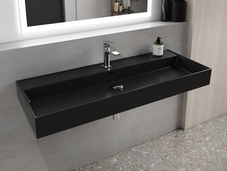 Schwarzes Waschbecken mit Armatur und beleuchtetem Spiegel im Badezimmer.