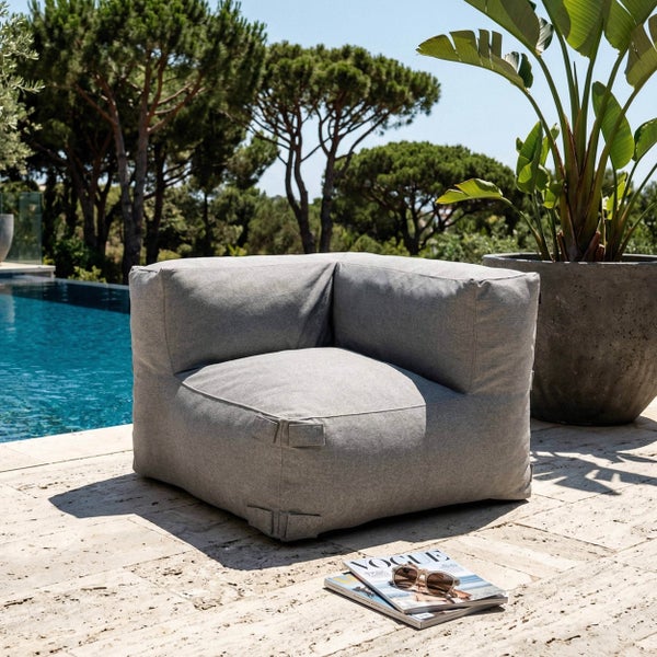 Grauer Outdoor-Eck-Loungesessel aus Textil auf einer Steinterrasse am Pool.
