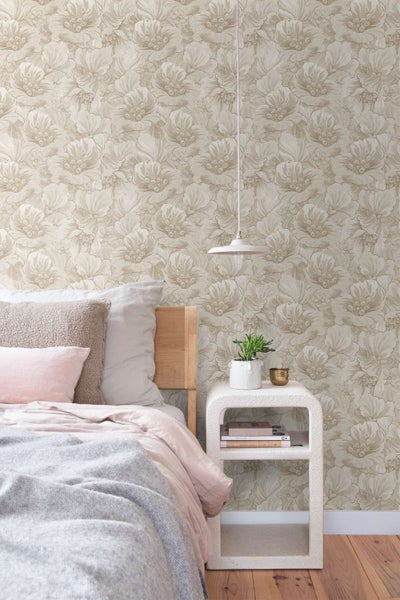 Schlafzimmer mit Vliestapete mit Blumenmuster, dazu ein Holzbett, ein Nachttisch mit Pflanze und eine Pendelleuchte vor einer gemusterten Wand.
