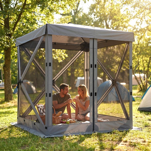 Ein Paar sitzt in einem grauen Pop-up-Pavillon mit Insektenschutzgitter auf einer hellen Wiese beim Picknick.