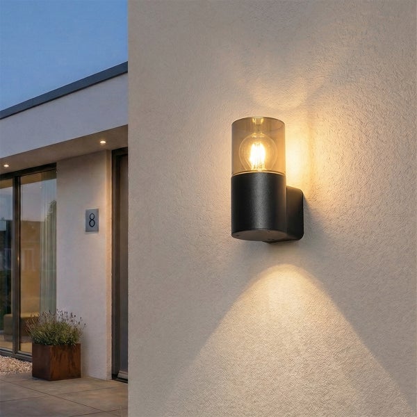 Moderne Außenwandleuchte mit Glaseinsatz an strukturierter Hauswand, Lichtstrahl nach oben und unten gerichtet, Eingangsbereich eines Wohnhauses.