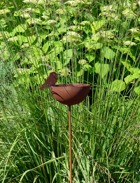 Gartenstecker aus Metall in Edelrostoptik mit kleiner Vogeltränke und Vogel-Figur als Gartendekoration im Beet.