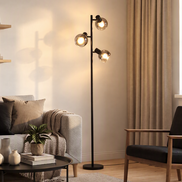 Moderne Stehleuchte mit drei Glaskugeln in einem Wohnzimmer mit Sofa und Sessel.