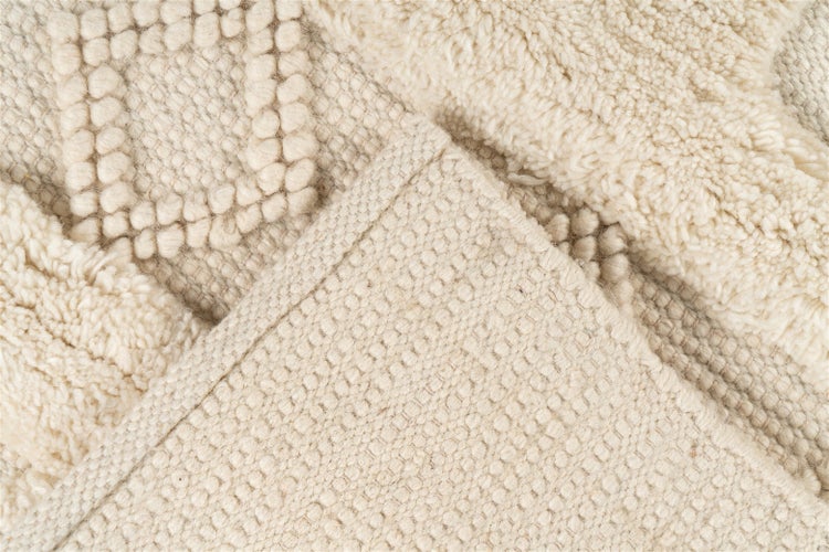 Detailaufnahme eines Teppichs mit verschiedenen Texturen wie Hochflor und Schlingenstruktur sowie der Rückseite.