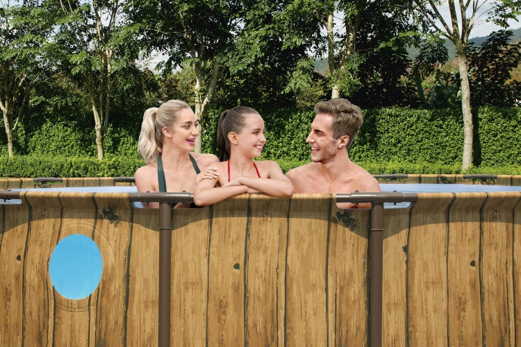 Familie in einem Aufstellpool mit Wänden in Holzoptik und rundem Sichtfenster im Garten.