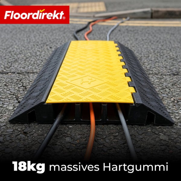 Floordirekt Logo. Robuste gelb-schwarze Kabelbrücke aus 18 Kilogramm massivem Hartgummi auf Asphalt mit fünf Kanälen für Kabel.