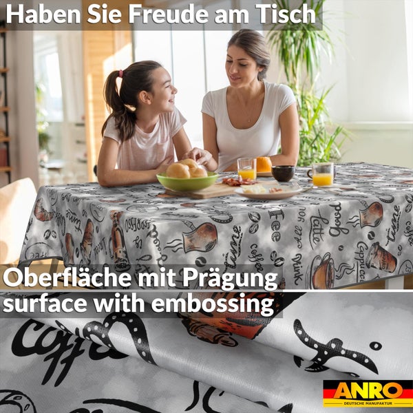 Eine Frau und ein Mädchen sitzen an einem Tisch mit einer gemusterten Wachstuch-Tischdecke mit Kaffee-Motiven und geprägter Oberfläche.