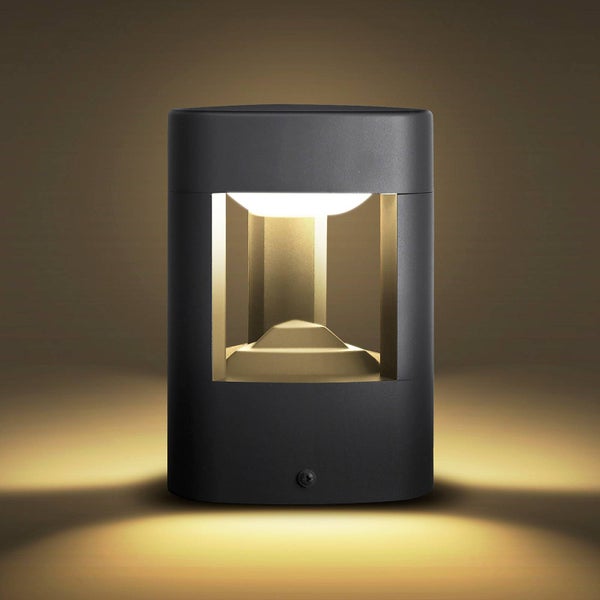 Moderne schwarze Außenwandleuchte in zylindrischer Form mit warmweißem Lichtaustritt.