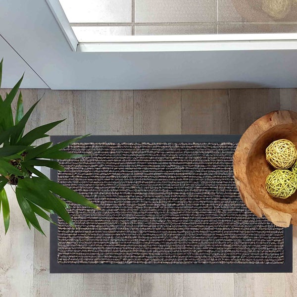 Fußmatte mit Streifenmuster, Topf mit Pflanze und Holzschale mit dekorativen Kugeln