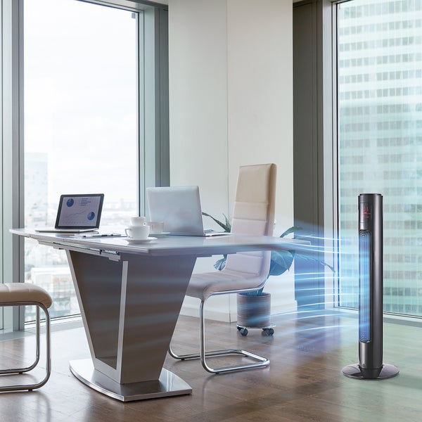 Turmventilator in einem modernen, hellen Büro mit Schreibtisch, Laptop und Blick auf die Skyline durch große Fenster.