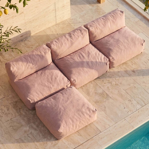 Modulares Gartensofa mit drei Sitzelementen und einem Hocker auf einer hellen Steinterrasse am Pool.