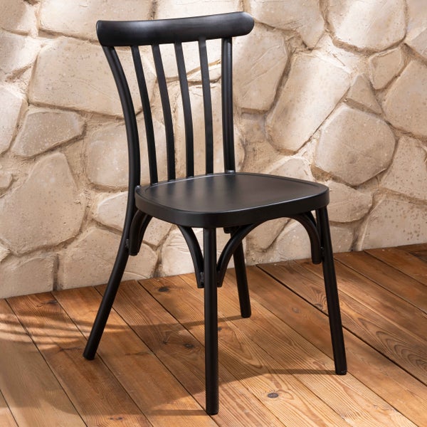 Schwarzer Gartenstuhl aus Metall mit Rückenlehne aus vertikalen Streben auf einer Holzterrasse vor einer Natursteinwand.