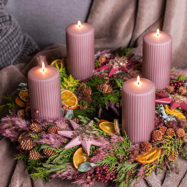 Adventskranz mit vier brennenden Kerzen, Tannenzweigen, Sternen und Orangenscheiben