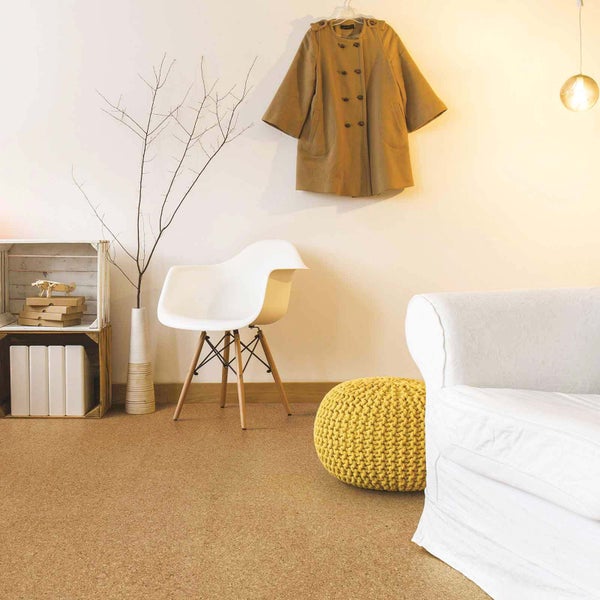 Moderner Wohnraum mit Korkboden, weißem Sofa, gelbem Strick-Pouf, weißem Stuhl und Holzregal.