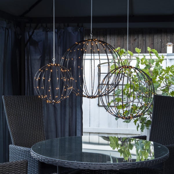 Dekorative Gartenbeleuchtung mit drei LED-Kugeln über einem Gartentisch