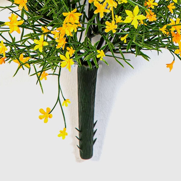 Künstliches Gesteck mit gelben Blüten, grünen Blättern und einer strukturierten dunklen Vase.