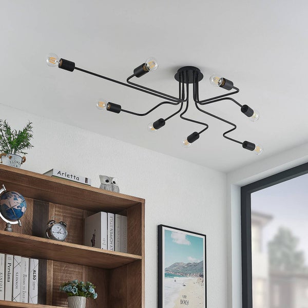 Schwarze Deckenleuchte mit acht Armen und Glühbirnen in einem Wohnraum mit Bücherregal und Dekoration.