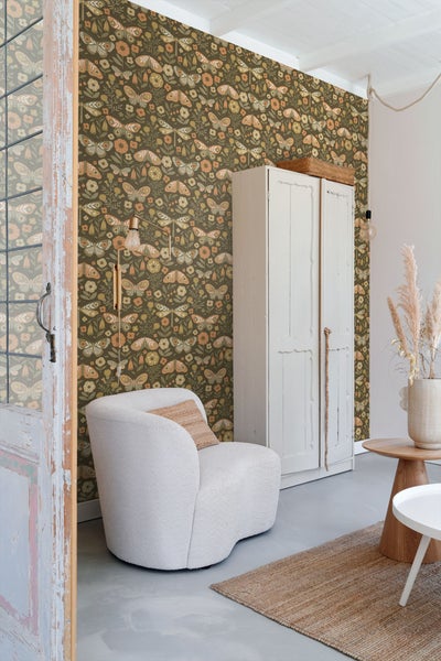 Dekoratives Zimmer mit Tapete mit Schmetterlingsmuster, Sessel und Schrank