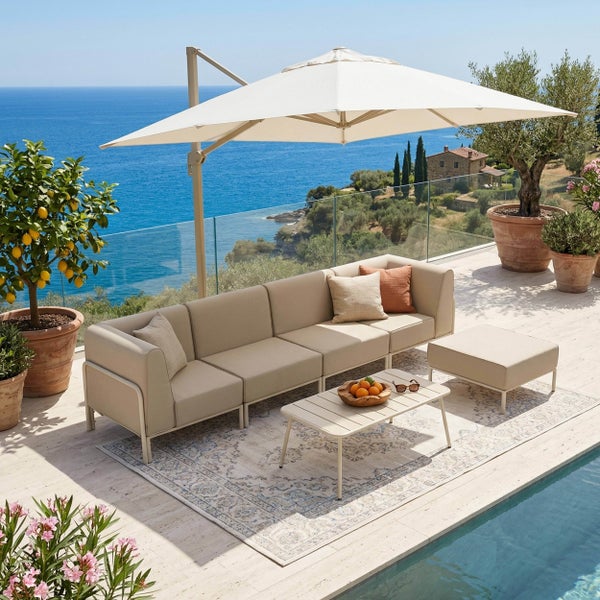 Modernes beiges Lounge-Set mit Sofa, Tisch und Hocker auf einer hellen Terrasse mit Pool, Meerblick und großem Ampelschirm.