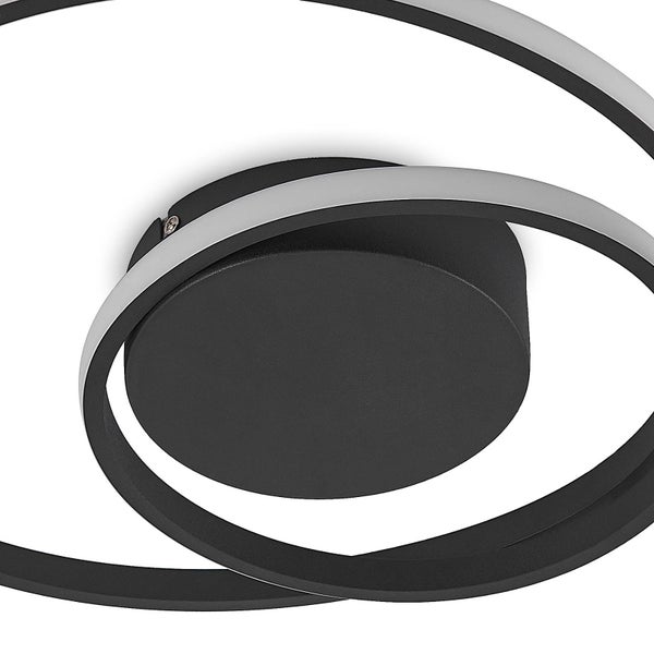 Detailansicht einer modernen LED-Deckenleuchte mit rundem schwarzem Sockel und geschwungenen Lichtringen.