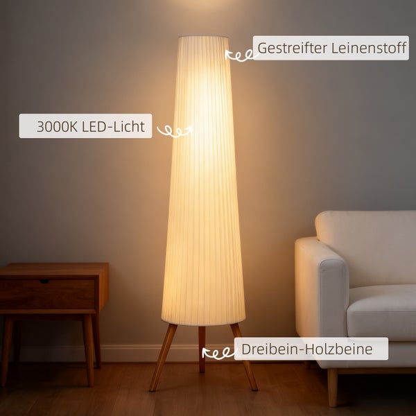Moderne Stehleuchte mit Dreibein-Holzbeinen, gestreiftem Leinenschirm und 3000 Kelvin LED-Licht. Warm beleuchtetes Wohnzimmer mit Sofa und Tisch.