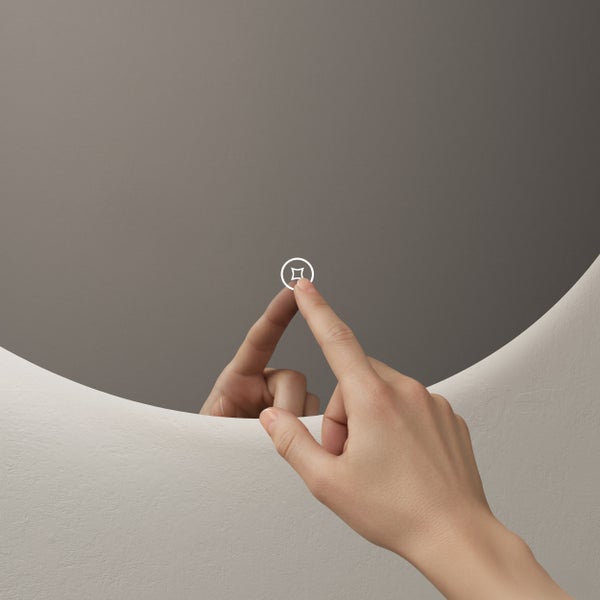 Nahaufnahme einer Hand, die das Touch-Sensor-Symbol auf einem runden Badezimmerspiegel berührt.