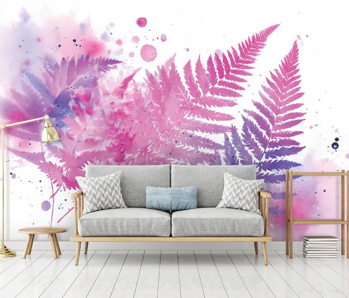 Fototapete mit Aquarell Farnwedeln in Rosa und Violett hinter einem grauen Sofa in einem hellen und modern eingerichteten Wohnzimmer.