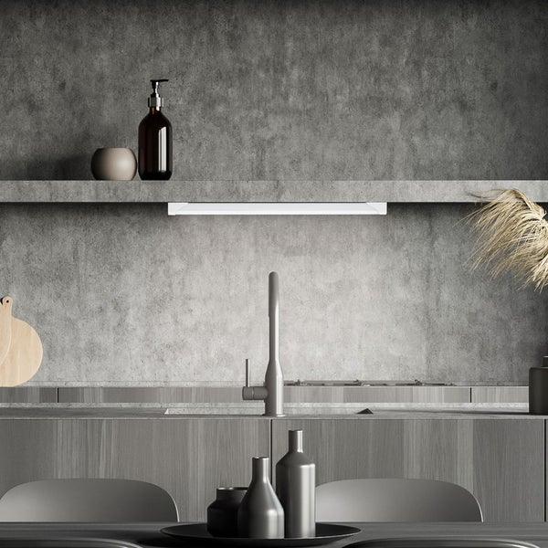 Moderne Küche mit Betonoptik-Wand und einer LED-Unterbauleuchte unter einem Regal über der Spüle.