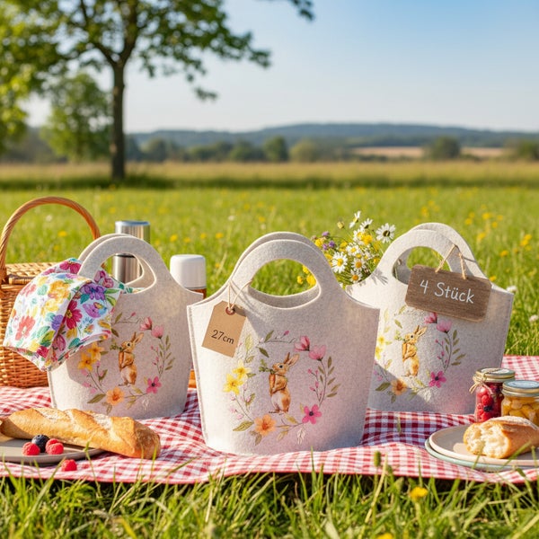 Drei Deko Osterkörbe aus Filz mit Hasenmotiv und Blumenmuster auf einer Picknickdecke im Freien.