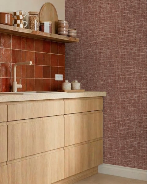 Moderne Küche mit hellen Holzunterschränken, rötlichem Fliesenspiegel und strukturierter Tapete in Terrakotta-Optik.