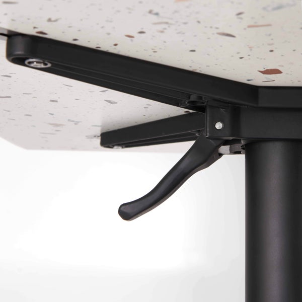 Klappmechanismus unter einer Tischplatte in Terrazzo-Optik mit schwarzem Metallhebel und Gestell.